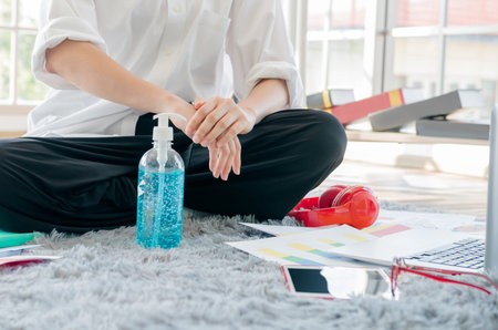 A woman work from home is using a sanitizing gel hand washing to protect against the Covid-19 virus...