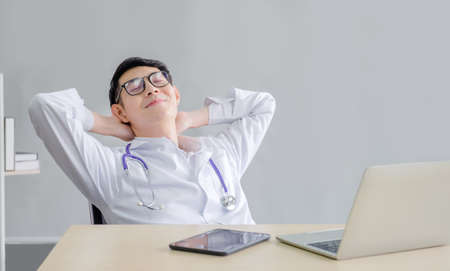 smart Doctor man working with technology notebook computer, mobile phone and tablet break time relax after coronavirus cases finish the job at the workplace of hospitalの写真素材