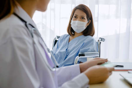 patients in a wheelchair talking with woman Doctor.の写真素材