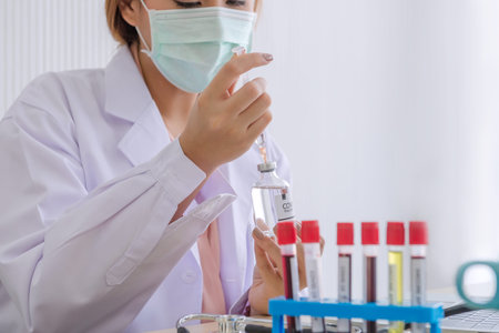 A female doctor is using a syringe in the office of a blood test hospital, a patient infected with...