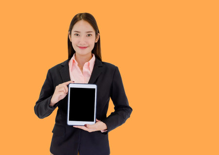 Asian businesswomen showing tablet On an orange background and free space to put text