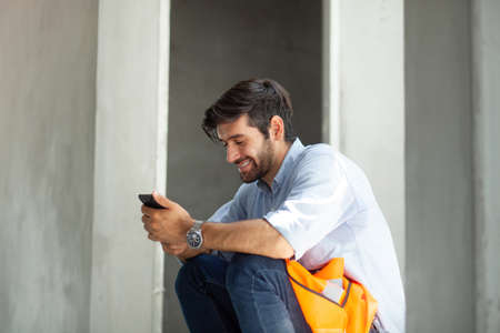 Caucasian man business worker sitting at a construction site. Sit and smile happily. Workers resting at a construction siteの写真素材