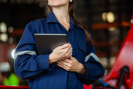 Female engineer, maintenance worker holding a laptop computer controls an automated robotic hand...