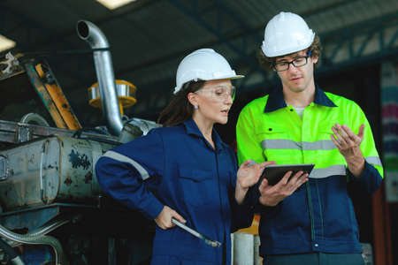 Two engineers look at information on how to maintain and maintain equipment, explain in detail the work in a machine manufacturing plant.の写真素材