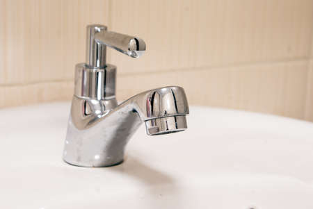 One chrome faucet in washbowl in bath room o white pileの写真素材