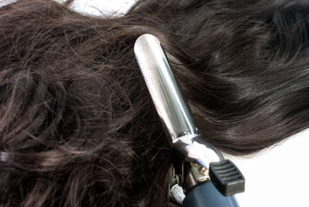 Electric curling iron and hair on white backgroundの写真素材
