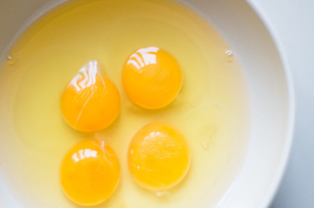 Four yellow egg yolks in a white bowl.
