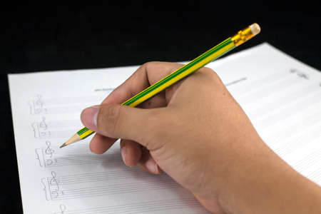 composing musical notes on paper with pencil on black の写真素材