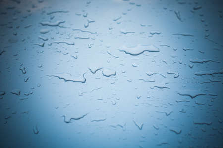 water drop on  a blue metallic surface with vignetteの写真素材