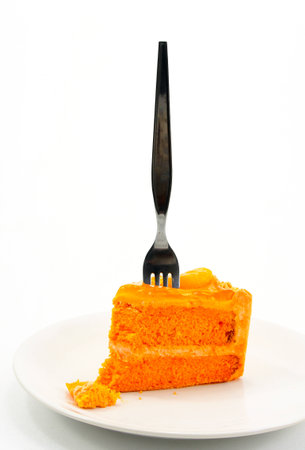 Orange cake with fork on white plateの写真素材