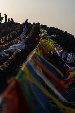 mountain peak with tibetan flags hanging on the rocks during sunset in uttarakhandの写真素材