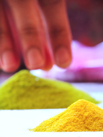 pile of two vibrant rangoli colors or colored sand, green and yellow with magenta in background...