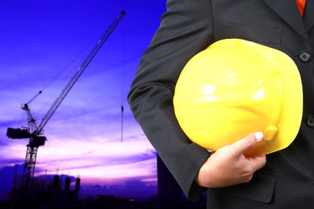 engineer holding yellow helmet for workers security on background of new highrise  buildings and ...