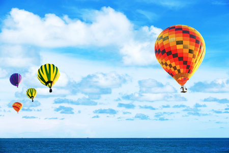 Colorful hot air balloon fly over the blue seaの写真素材