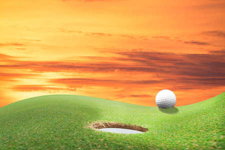 golf ball and hole on a fieldの写真素材