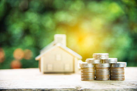 coin stack with house model, savings plans for housing green backgroundの写真素材