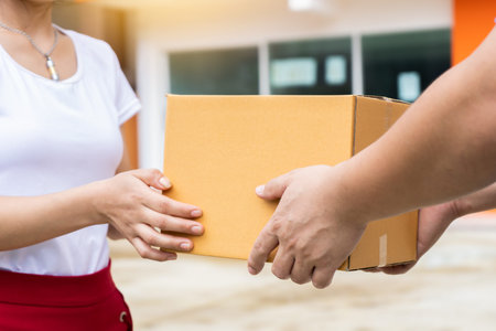 delivery man holding pile of cardboard boxes in front delivering package to customer, close up at hand and boxの写真素材
