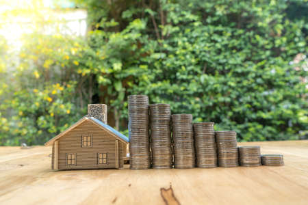 small house with Coin stacks on green background. The concept of purchase of habitationの写真素材