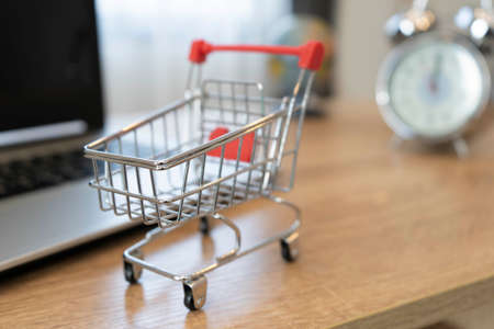 Online shopping concept. Shopping cart, laptop on the deskの写真素材