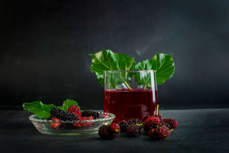 Fresh mulberry fruit in a bowl and juice in a glassの写真素材