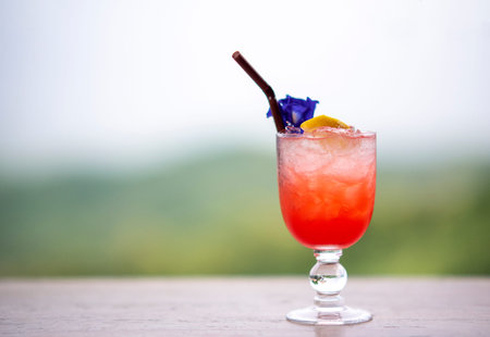 Italian red cold soda on wooden table in natural atmosphere against blurred background.
