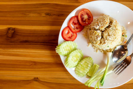 Crab meat fried rice and vegetable on a wooden table.の写真素材