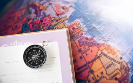 a compass placed on a notebook on the map background travel geographic navigation concept backgroundの写真素材
