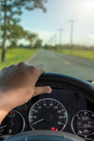 The driver's hand holds the steering wheel in the car. vertical view travel conceptの写真素材