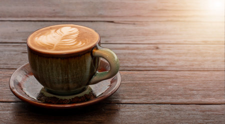 coffee in green cup on wooden table in cafeの写真素材