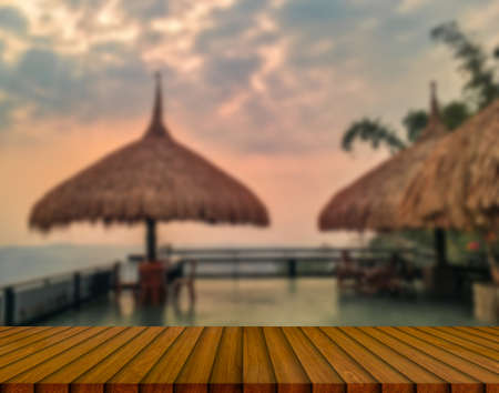 Wooden table and blur of beauty, sunset sky, and mountains as background.の写真素材