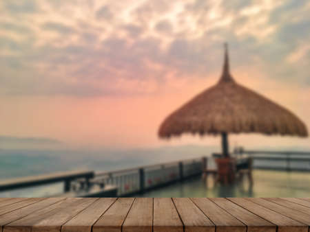 Wooden table and blur of beauty, sunset sky, and mountains as background.の写真素材