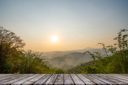 Wooden table and blur of beauty, sunset sky, and mountains as background.