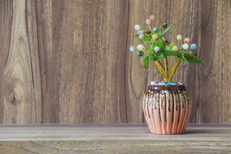 Fake flowers in a vase placed on a table on a wooden table with copy space for design wood grain vintage background.の写真素材