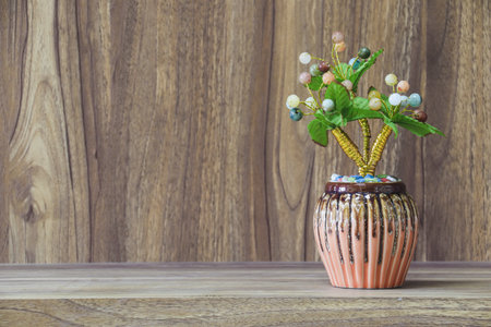 Fake flowers in a vase placed on a table on a wooden table with copy space for design wood grain vintage background.の写真素材