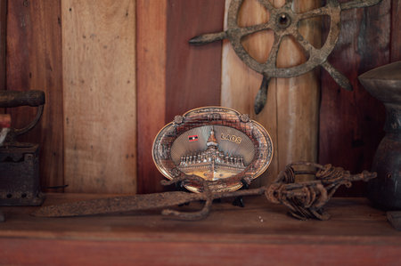 Antique compass on a wooden shelf in a rustic room.の写真素材