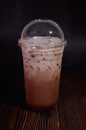 Iced coffee in plastic cup on wooden table background. Selective focus.の写真素材