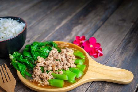 Stir fried Hong Kong kale with pork chops on a wooden table.の写真素材