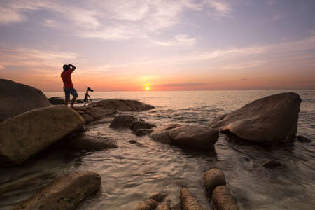 the photographer on a rock when sunsetの写真素材