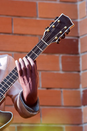 Hand holding a guitar neck with Brick background