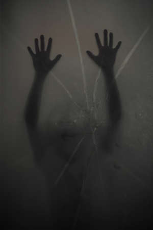 Horror behind the matte glass crack Blurry hand and body figure abstraction.の写真素材