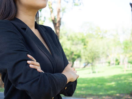 asia business woman wearing suit cross arm  and teeth smile face standing in park copy spaceの写真素材
