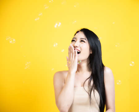 portrait asian woman smile face Blowing Bubbles with yellow backgroundの写真素材