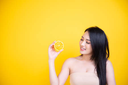 Beautiful Asian women smile happyness holding fresh orange slide with a yellow background.Squeeze Fresh oranges healthy fruits that are vitamin C.の写真素材
