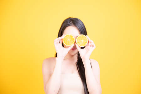 Beautiful Asian women smile happyness holding fresh orange slide with a yellow background.Squeeze Fresh oranges healthy fruits that are vitamin C.の写真素材