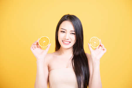 Beautiful Asian women smile happyness holding fresh orange slide with a yellow background.Squeeze Fresh oranges healthy fruits that are vitamin C.の写真素材