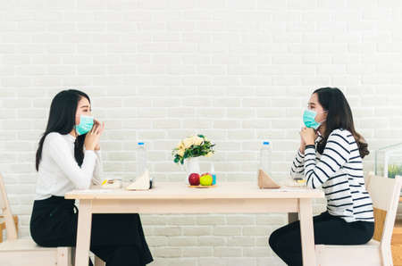 Two beautiful Asian women are sitting and eating apart social distancing concept new normal lifestyleの写真素材