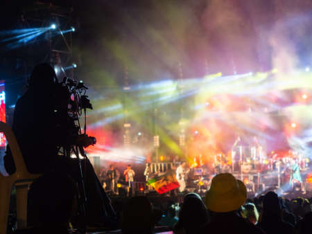 crowd at concert - summer music festival in front of bright stage lights. Dark background, smoke, concert spotlights.people dancing and having fun in summer festival party outdoor