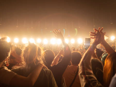 crowd at concert - summer music festival in front of bright stage lights. Dark background, smoke, concert spotlights.people dancing and having fun in summer festival party outdoorの写真素材