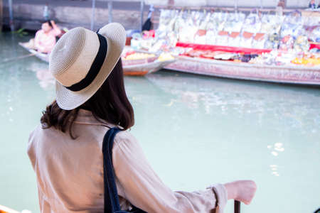 asia female tourists wearing hat holding camera and smartphone take photo vlog live . Beautiful woman take taxi boat visiting Damnoen Saduak floating market,Ratchaburi.の写真素材