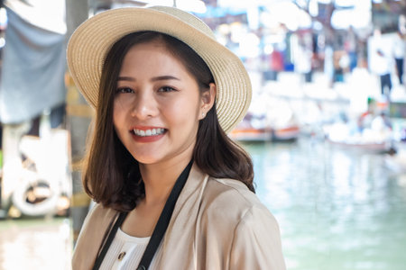 asia female tourists wearing hat holding camera and smartphone take photo vlog live . Beautiful woman take taxi boat visiting Damnoen Saduak floating market,Ratchaburi.の写真素材